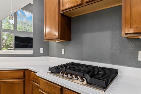 A modern kitchen with a white countertop and a black stove top.