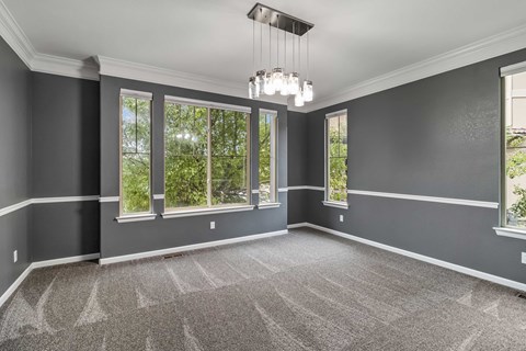 A room with grey walls and a carpeted floor with a chandelier hanging from the ceiling.