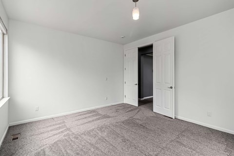 A room with a carpeted floor and a doorway leading to another room.