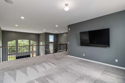 A spacious living room with a flat screen TV mounted on the wall.