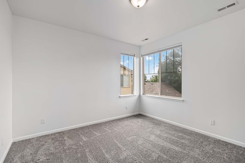 A spacious room with a carpeted floor and a window overlooking a street.