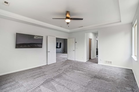A spacious room with a ceiling fan and carpeted floor.