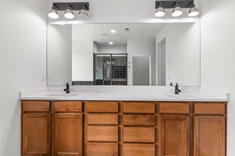 A bathroom vanity with a white countertop and wooden cabinets.