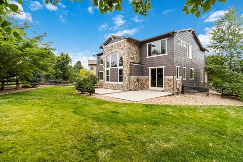 A house with a stone wall and a large lawn.