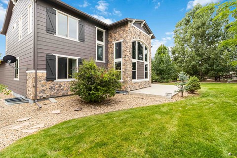 A house with a grey exterior and a stone wall on the side.