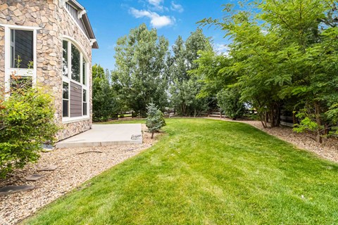 A house with a stone wall and a green lawn.