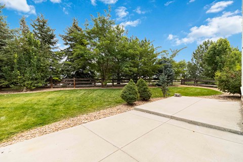 A driveway leads to a house with a green lawn and trees.