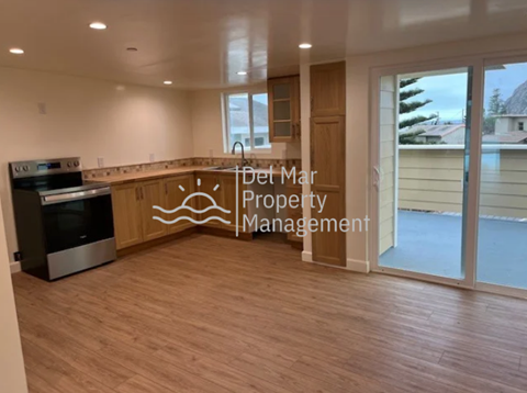 A kitchen area with a stove and a countertop with a logo for Det Mar Property Management.