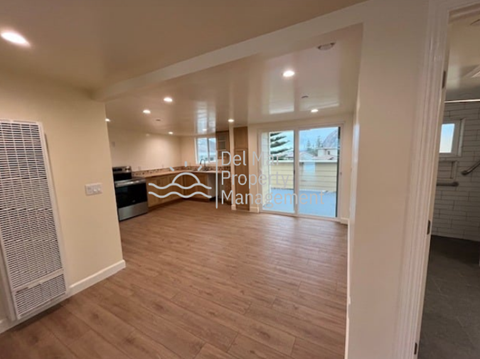 A spacious room with wooden flooring and a large window.