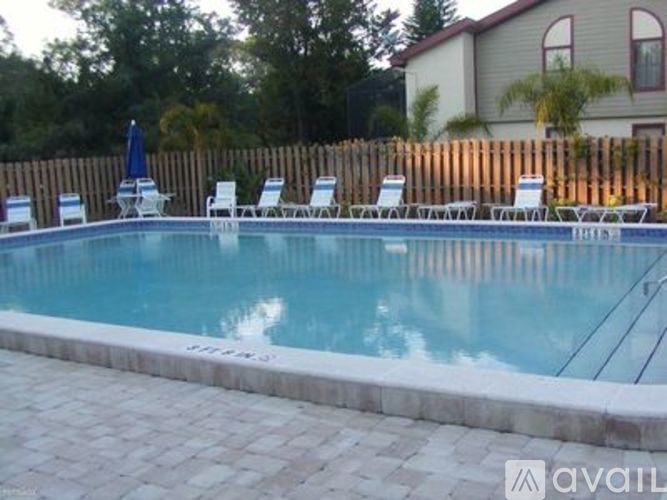 A pool with a white fence and chairs around it.