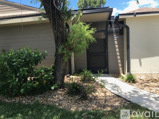 A tree is in front of a house with a ladder in the yard.
