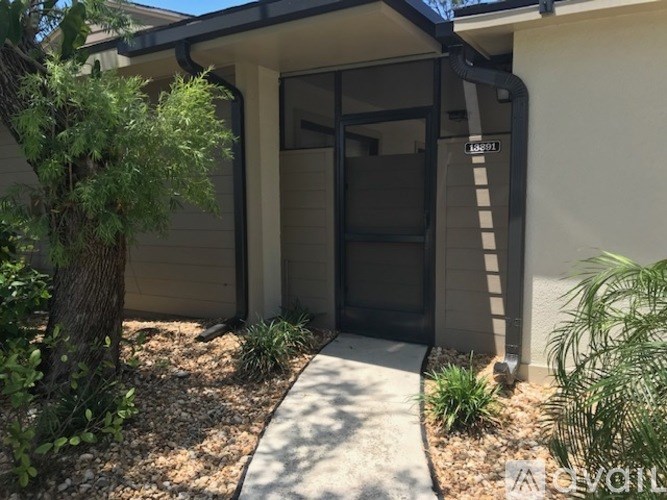 A modern house entrance with a glass door and a small garden.
