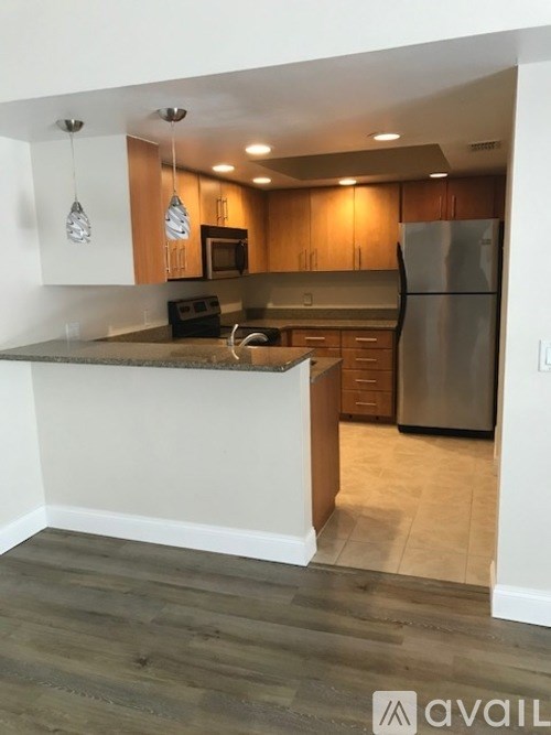 A kitchen with wooden cabinets and a stainless steel refrigerator.