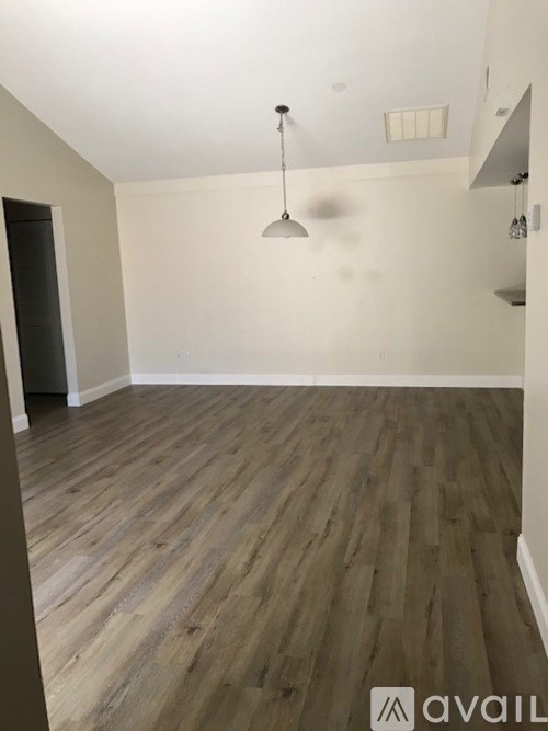 A room with wooden flooring and a hanging light fixture.