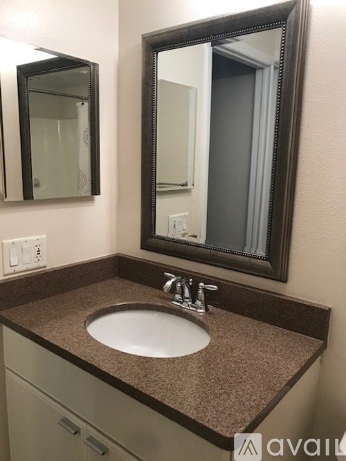 A bathroom sink with a brown counter top and a large mirror above it.