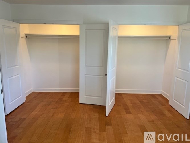 A room with wooden floors and white walls with two doors.