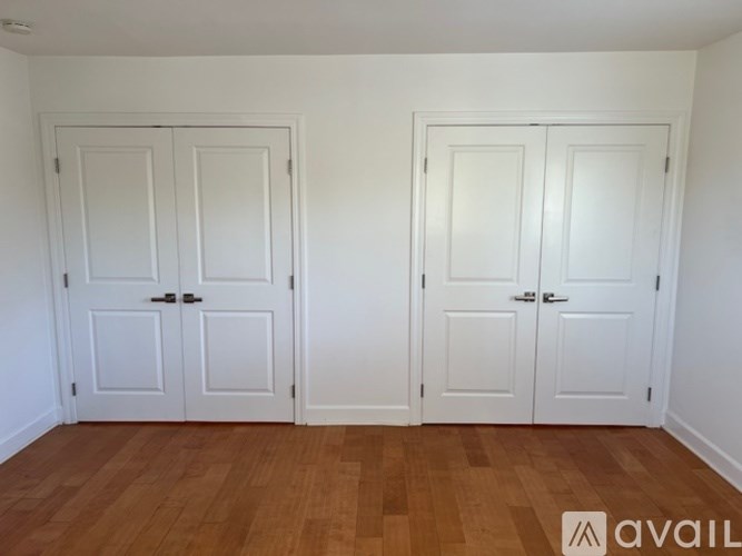Two white doors in a room with wooden floors.