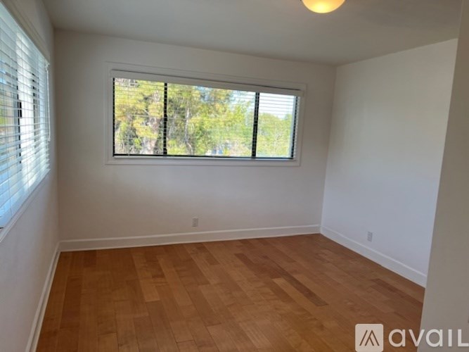 A room with wooden flooring and a window with blinds.
