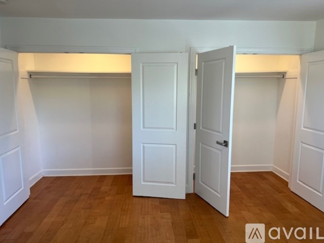 A room with a white door and wooden flooring.