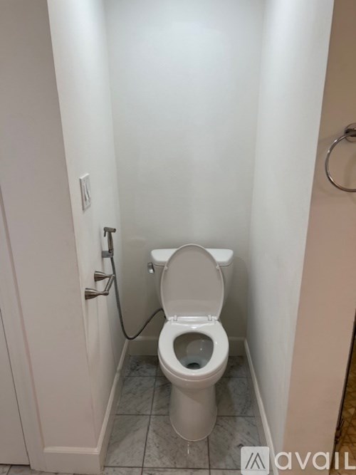 A white toilet in a small bathroom with a closed toilet paper roll.