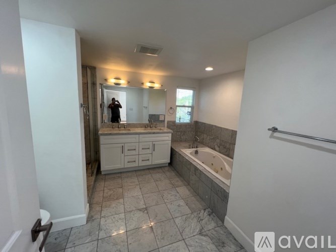 A bathroom with a tub, sink, and mirror.
