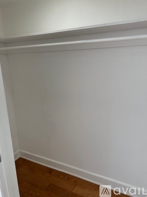 A white wall with a wooden floor and a white door.
