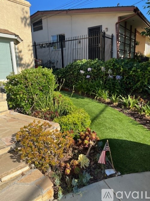 A small garden with a flag and a house in the background.