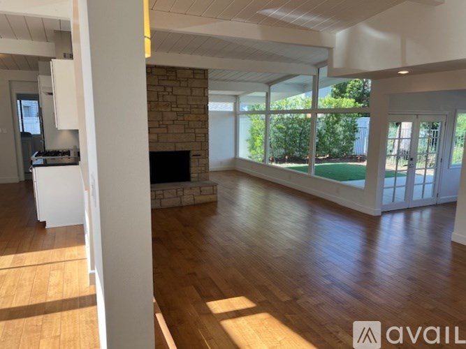 A spacious living room with wooden floors and a stone fireplace.
