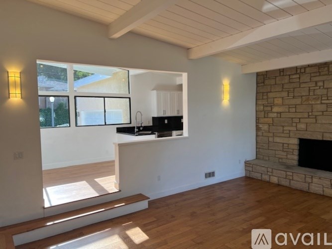 A modern living room with a fireplace and a kitchen area in the background.