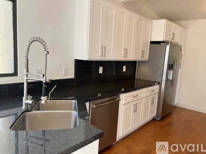 A kitchen with white cabinets and a black countertop.