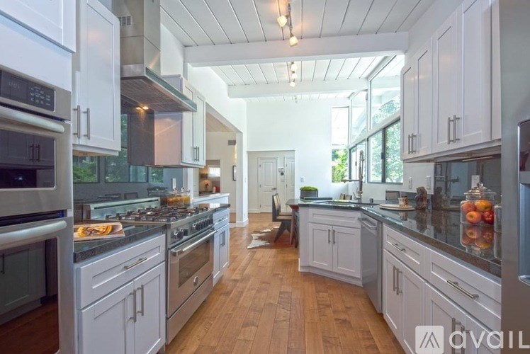 A modern kitchen with white cabinets and stainless steel appliances.