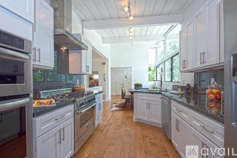 A modern kitchen with white cabinets and stainless steel appliances.