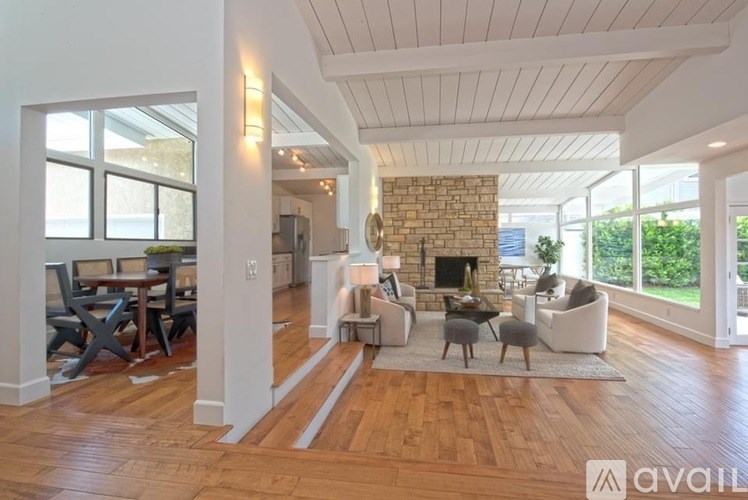 A spacious living room with a stone fireplace and hardwood floors.