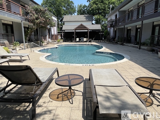 A pool surrounded by patio furniture and buildings.