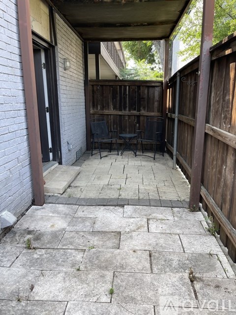 A patio with a table and chairs is surrounded by a wooden fence.