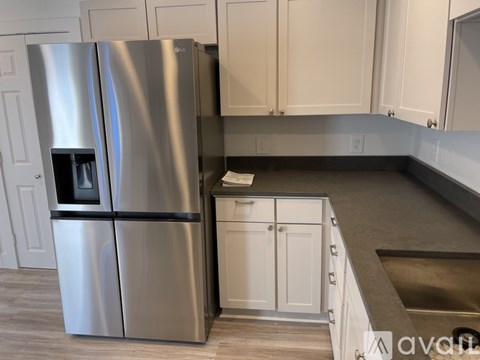 A stainless steel refrigerator with a black handle is in a kitchen.