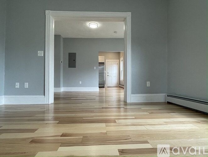 A room with wooden flooring and a white doorway leading to another room.