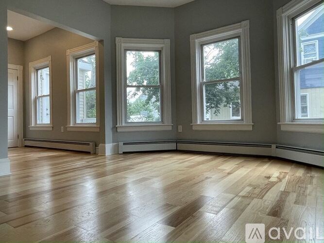 A room with wooden floors and three windows.