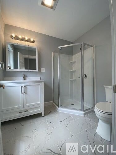 A bathroom with a toilet, sink, and mirror.
