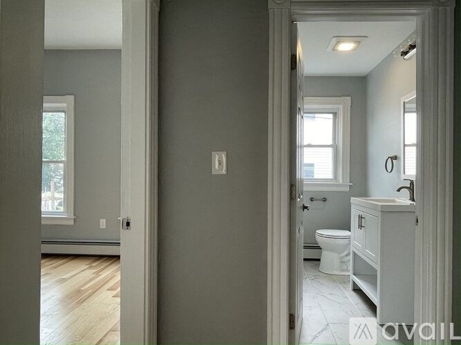 A bathroom with a toilet, sink, and mirror.