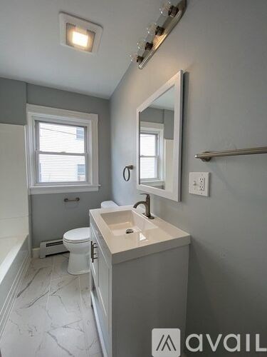 A bathroom with a toilet, sink, and mirror.