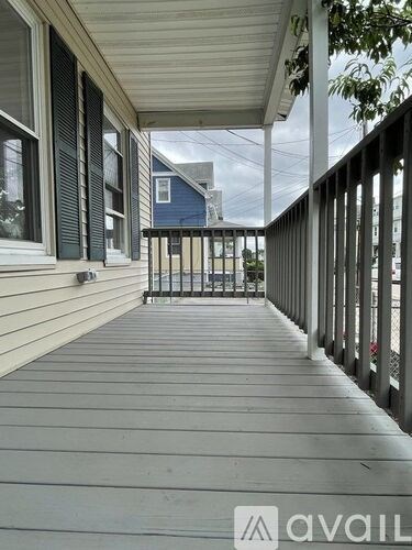 A wooden deck with a railing and a view of a house across the way.