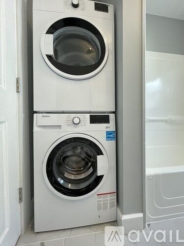 Two white front loading washing machines stacked on top of each other.