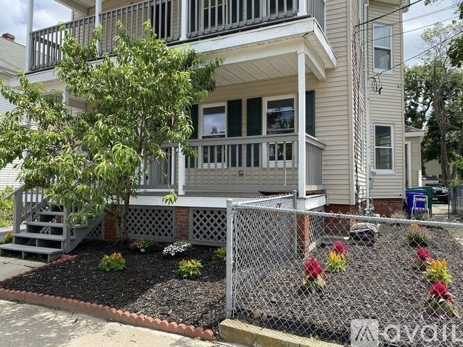 A house with a white porch and a tree in front.