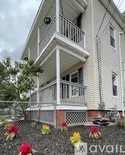 A house with a balcony and a fence with flowers in front.