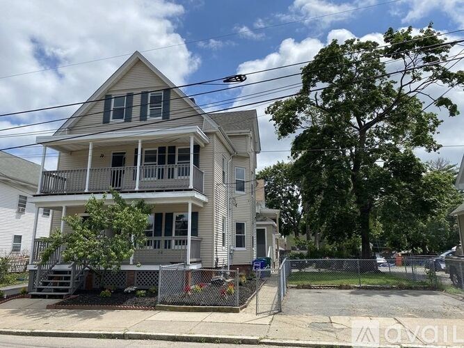 A two-story house with a grey and white exterior and a tree in front.