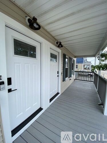 A white door with a black handle is on the left side of a porch.