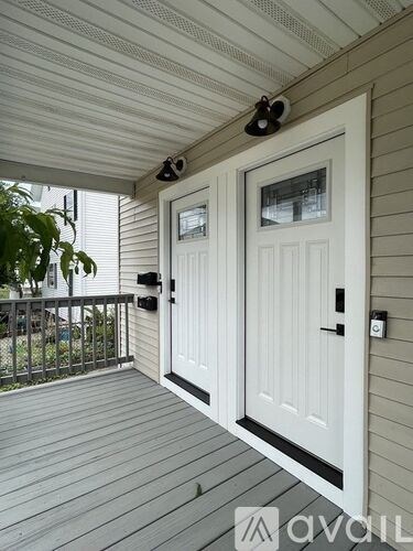 A white door with a black handle is on a porch.