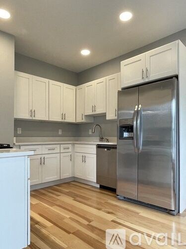 A kitchen with white cabinets and a stainless steel refrigerator.