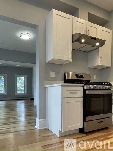 A kitchen with white cabinets and a stove top oven.
